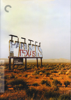 A weathered billboard stands in a dry, grassy desert landscape. Faded letters partially read PARIS, TEXAS. The sky is clear and pale, and distant hills are visible in the background.