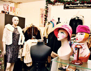 A vintage clothing store displays mannequins in retro outfits, hat stands with colorful wigs and hats, a black dress form, and racks of fur coats, creating a nostalgic and eclectic atmosphere.