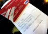 A close-up of a Bank of America debit card placed on top of a printed receipt from a store, showing some transaction details and a VISA logo on the card.