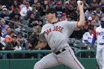 A baseball pitcher in a gray San Jose uniform prepares to throw a pitch during a game, with spectators watching from the stadium seats in the background.