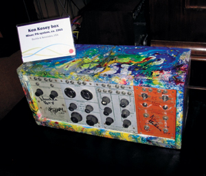 A vintage audio box covered in colorful, abstract paint splatters and signatures, displayed with a sign reading Ken Kesey box, Mixer, PA system, ca. 1965, Beats & Speeches, USA.