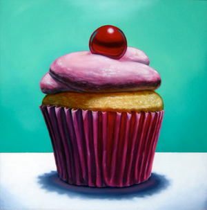 A cupcake with pink frosting and a red cherry on top, wrapped in a red paper liner, sits on a white surface against a teal background.