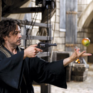 A man in a dark robe aims a revolver at an apple that he has tossed into the air indoors, with stone walls and wooden beams in the background.