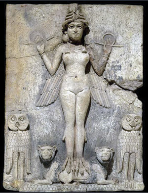 Ancient stone relief depicting a winged, nude female figure with bird talons, flanked by two owls and standing on lions. The figure holds symbols in each hand and wears a horned headdress. The background is a textured stone.