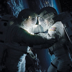 Two astronauts in spacesuits float in space above Earth, facing each other closely as if holding or assisting one another, with the planet’s curvature and city lights visible in the background.