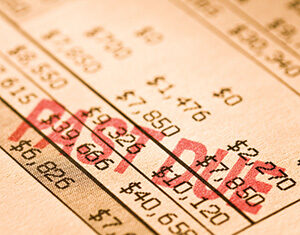 A close-up of a financial statement with numbers listed in columns. The word PAST DUE is stamped in red across the document, indicating overdue payments.
