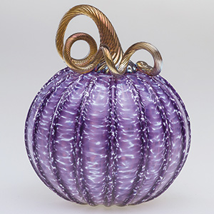 A decorative glass pumpkin with a ribbed, light purple body and a curly, gold-toned stem, displayed against a plain light background.