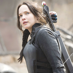 A young woman with dark braided hair wears black armor and carries a quiver of arrows on her back, looking determinedly into the distance.