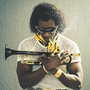 A person wearing sunglasses and a white mesh shirt holds a trumpet close to their chest. Smoke rises from the trumpet, and the person has a serious expression. The background is plain and textured.