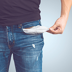 A person wearing blue jeans and a black shirt pulls out an empty pocket, suggesting they have no money.