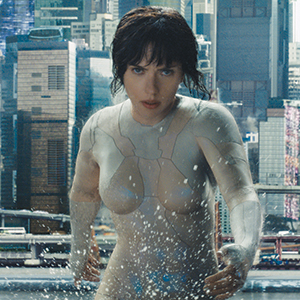 A woman in a form-fitting, futuristic bodysuit emerges from water in a cityscape with tall buildings in the background, looking determined and intense.