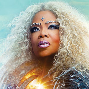 A woman with long, curly blonde hair gazes upward. She wears metallic makeup, jeweled face adornments, and a shiny outfit, with a glowing light near her chest against a blue sky background.
