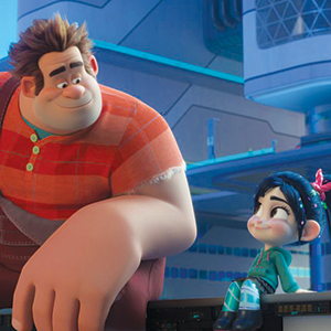 Animated characters Ralph and Vanellope sit together in a futuristic, brightly lit room. Ralph, large and wearing a red plaid shirt, smiles warmly at Vanellope, who is small with dark hair and a mint-green hoodie.