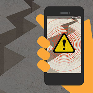 Illustration of a hand holding a smartphone displaying a warning symbol with red concentric circles, suggesting an emergency alert. The background shows cracks resembling earthquake damage.