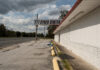 An empty parking lot beside a white, brick building with a sign that reads 777 Cyber Center under a cloudy sky; the area appears deserted and somewhat rundown.
