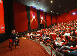 Crowd in a theater with two men on stage
