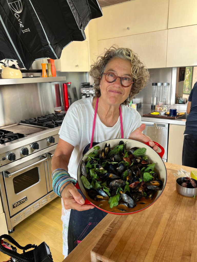 Woman in a kitchen holding up a pan full of food