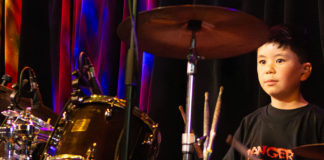 Young boy sitting behind a drum kit