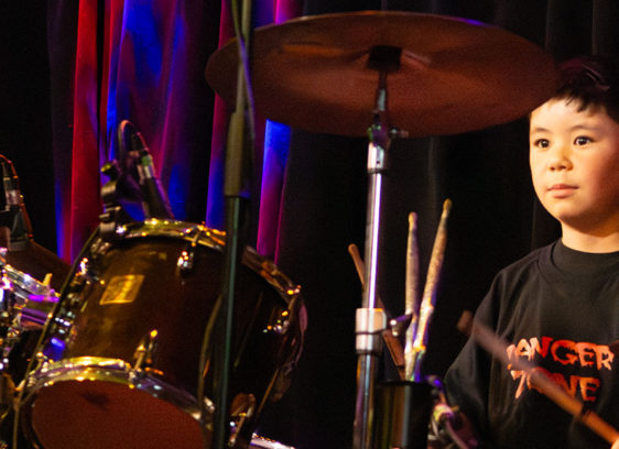 Young boy sitting behind a drum kit