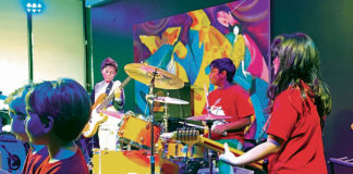 Young kids playing rock instruments on a stage