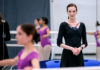 Ballerina in black leotard teaching a class of young dancers