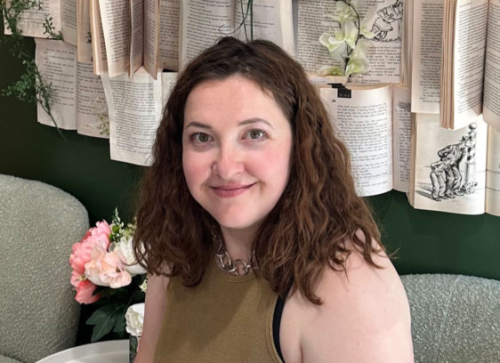 Woman sitting in front of a wall covered with pages from books
