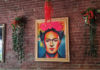 Framed illustration of Frida Kahlo hanging on a brick wall