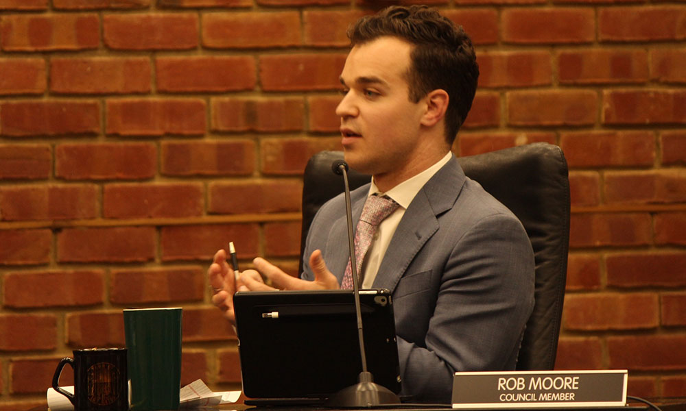 Man in profile sitting at a desk, looking at someone off camera