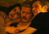 Three actors holding each other closely, appearing to be in bed
