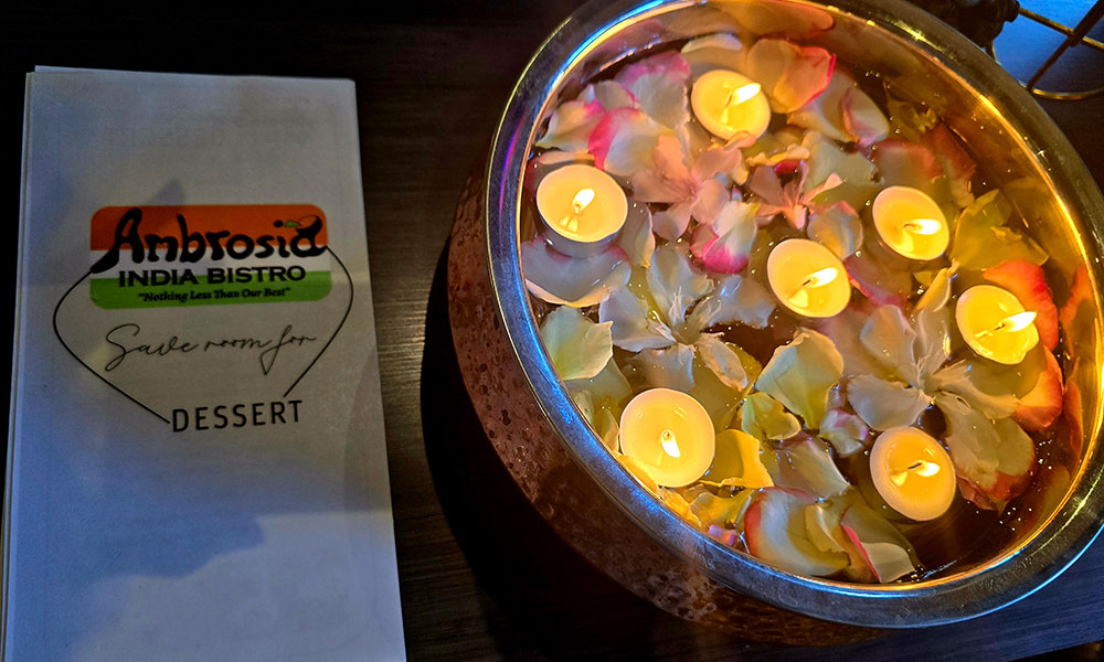 Ambrosia India Bistro menu next to floating candles and rose petals