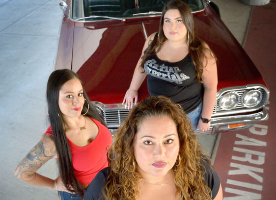 Three women standing in front of a car