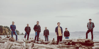 Seven people standing spaced out from each other at a beach