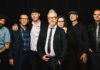 Seven people standing against a black background