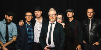 Seven people standing against a black background