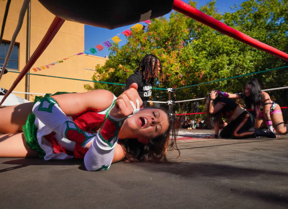 Wrestler lying down on the mat, hand outstretched and eyes closed