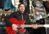 Man playing a red electric guitar in a music store
