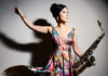 Woman in a flowing flowered dress holding a saxophone