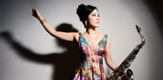 Woman in a flowing flowered dress holding a saxophone