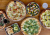 several pizzas and side dishes on a table