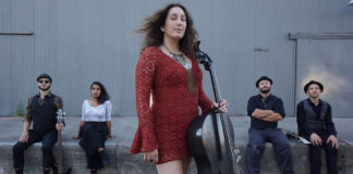 Woman holding a cello in front of four other bandmates