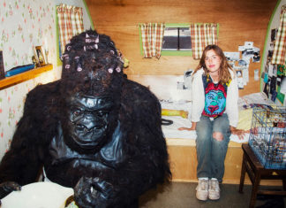 A gorilla made out of llama fur and a woman inside a trailer