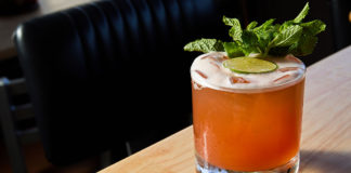 Cocktail with mint garnish sitting on a table