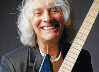 Man smiling and holding a guitar