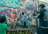 Musicians performing in front of a graffiti-covered wall