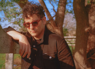 man leaning on a fence under a tree