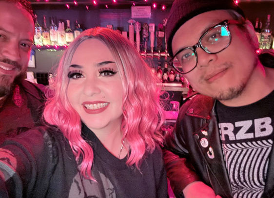 three people posing for a photo inside a nightclub