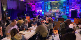 People sitting at long tables in a room with colorful lighting