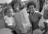 Black and white archival photo of African American families holding bags of food