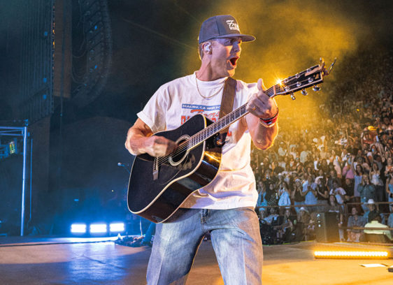 Man playing guitar on a stage with the audience behind him