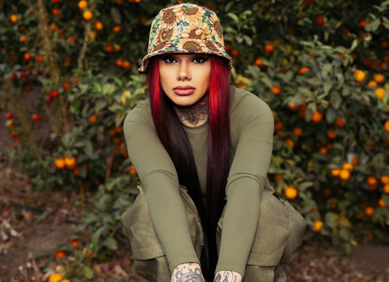 Woman with bright red hair crouching down and staring at the camera